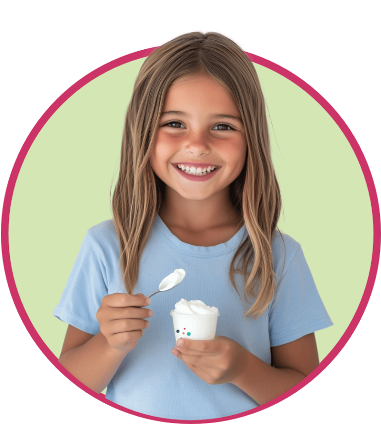 A smiling young girl with long brown hair, wearing a light blue shirt, holds a cup of frozen yogurt made for exocrine pancreatic insufficiency nutrition, against a light green background outlined with a pink circle.